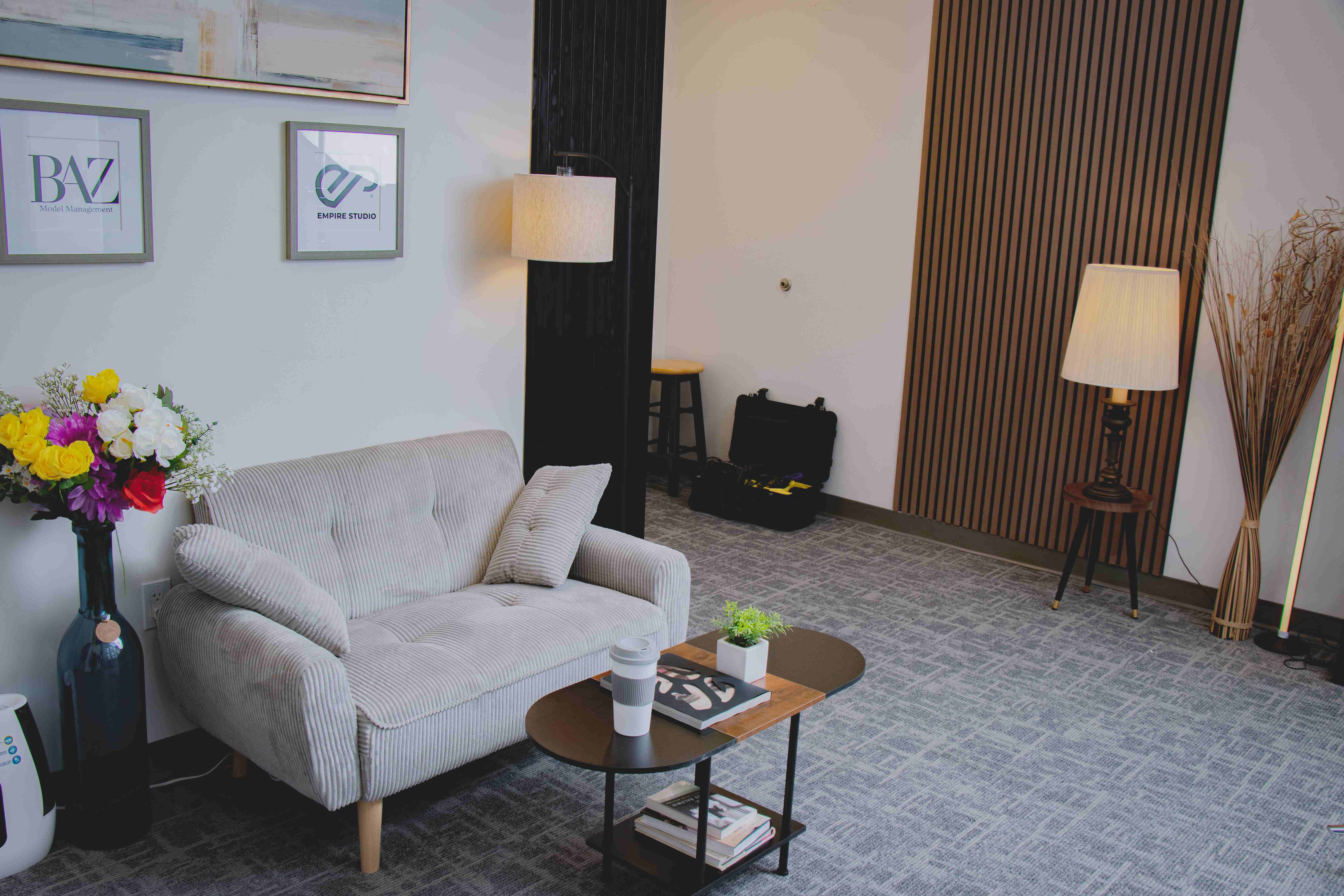 Empire Studio waiting room with a comfortable loveseat, warm lighting, and framed brand logos