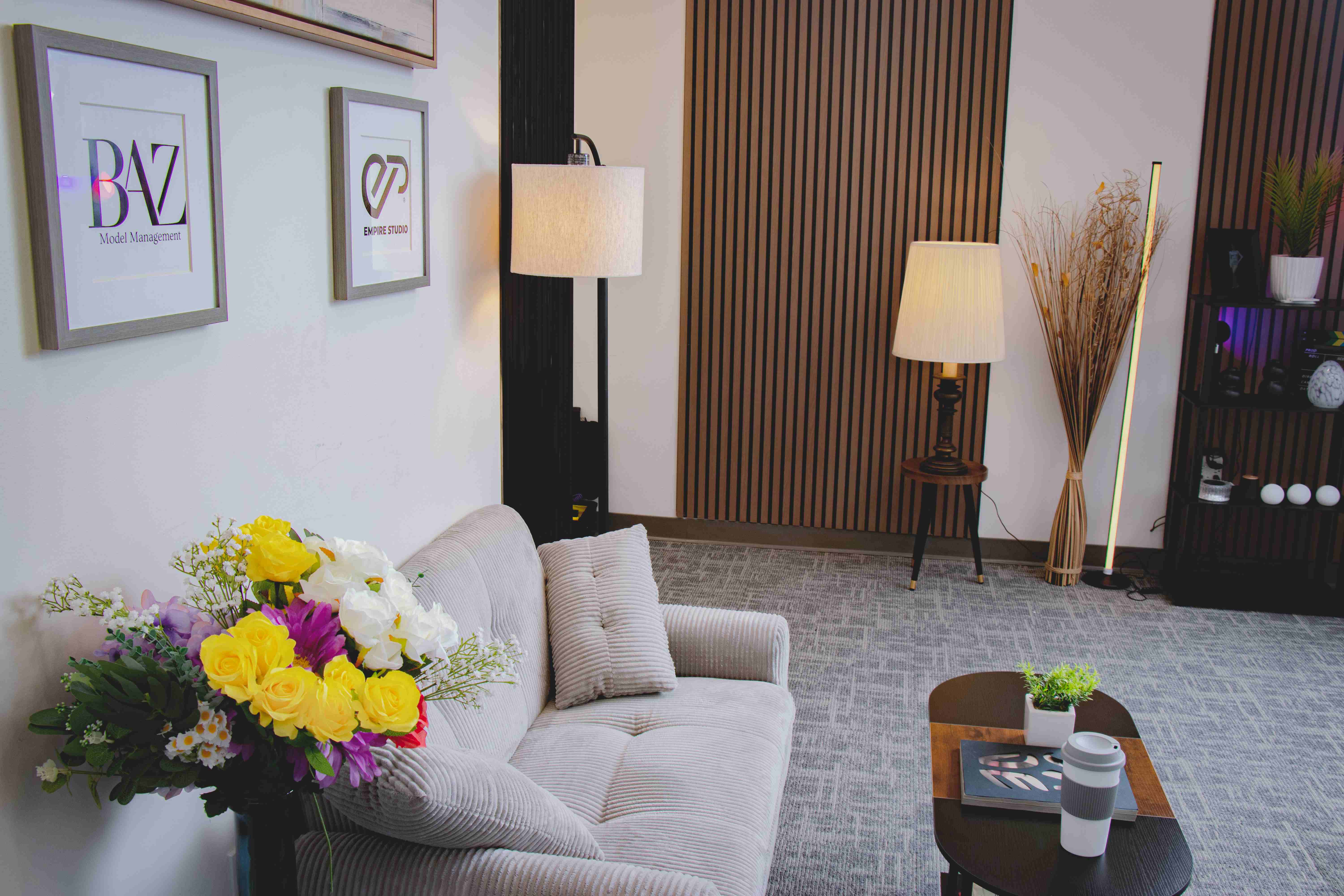 Empire Studio lounge with a corduroy sofa, fresh flowers, and framed studio logos on the wall