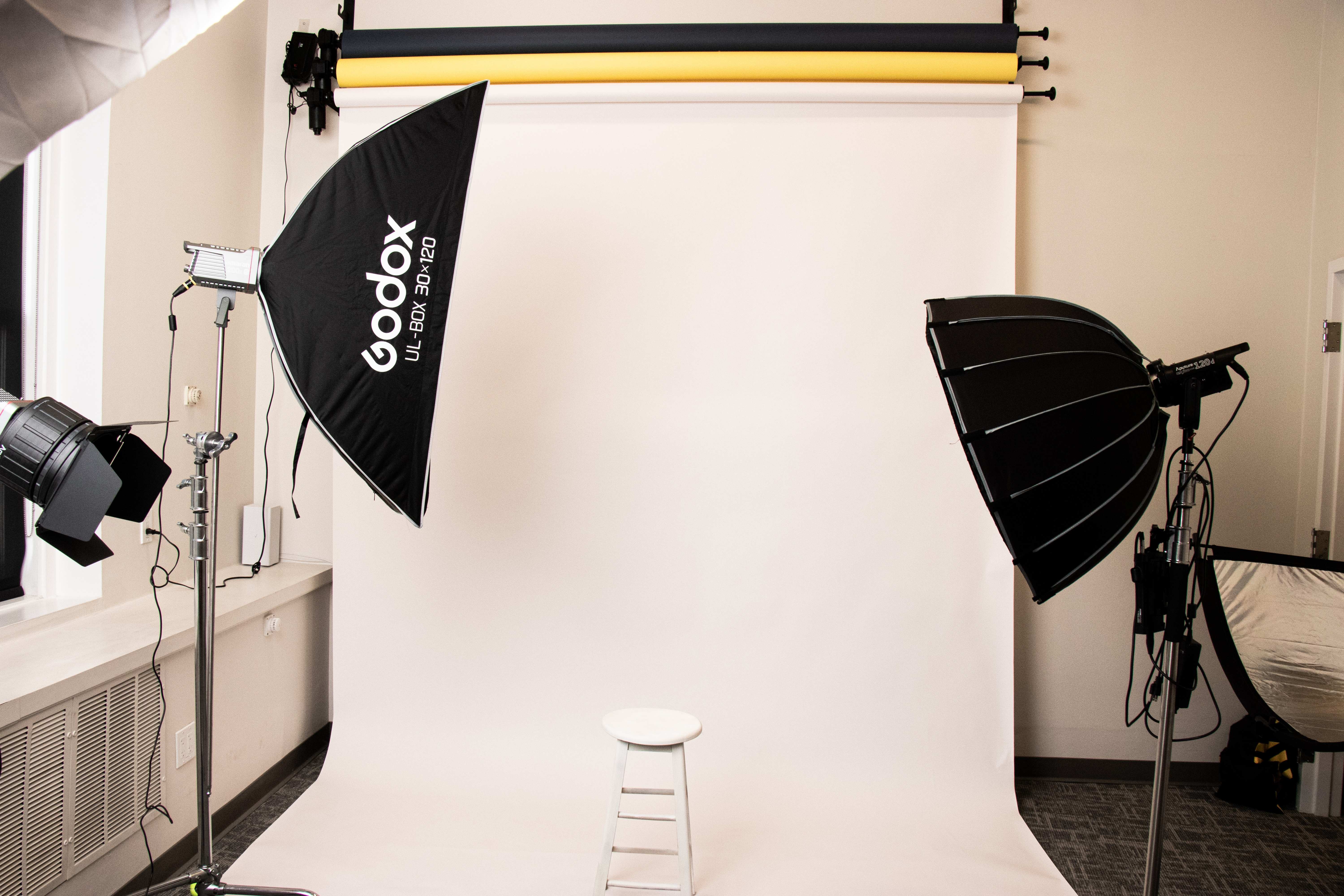 Clean white seamless backdrop flanked by a Godox softbox and a parabolic dome light
