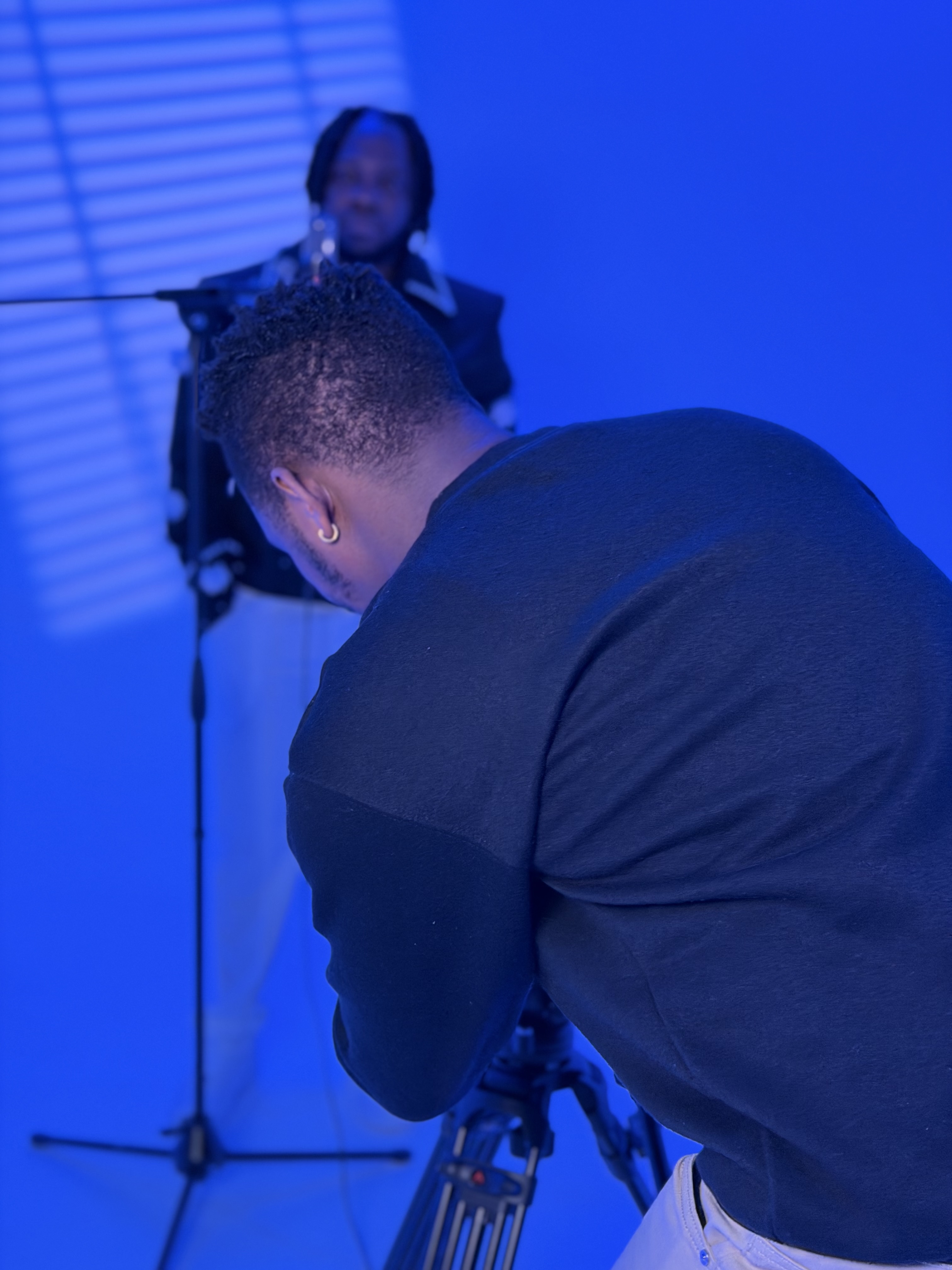 Videographer filming a guest speaking into a microphone under blue studio lighting
